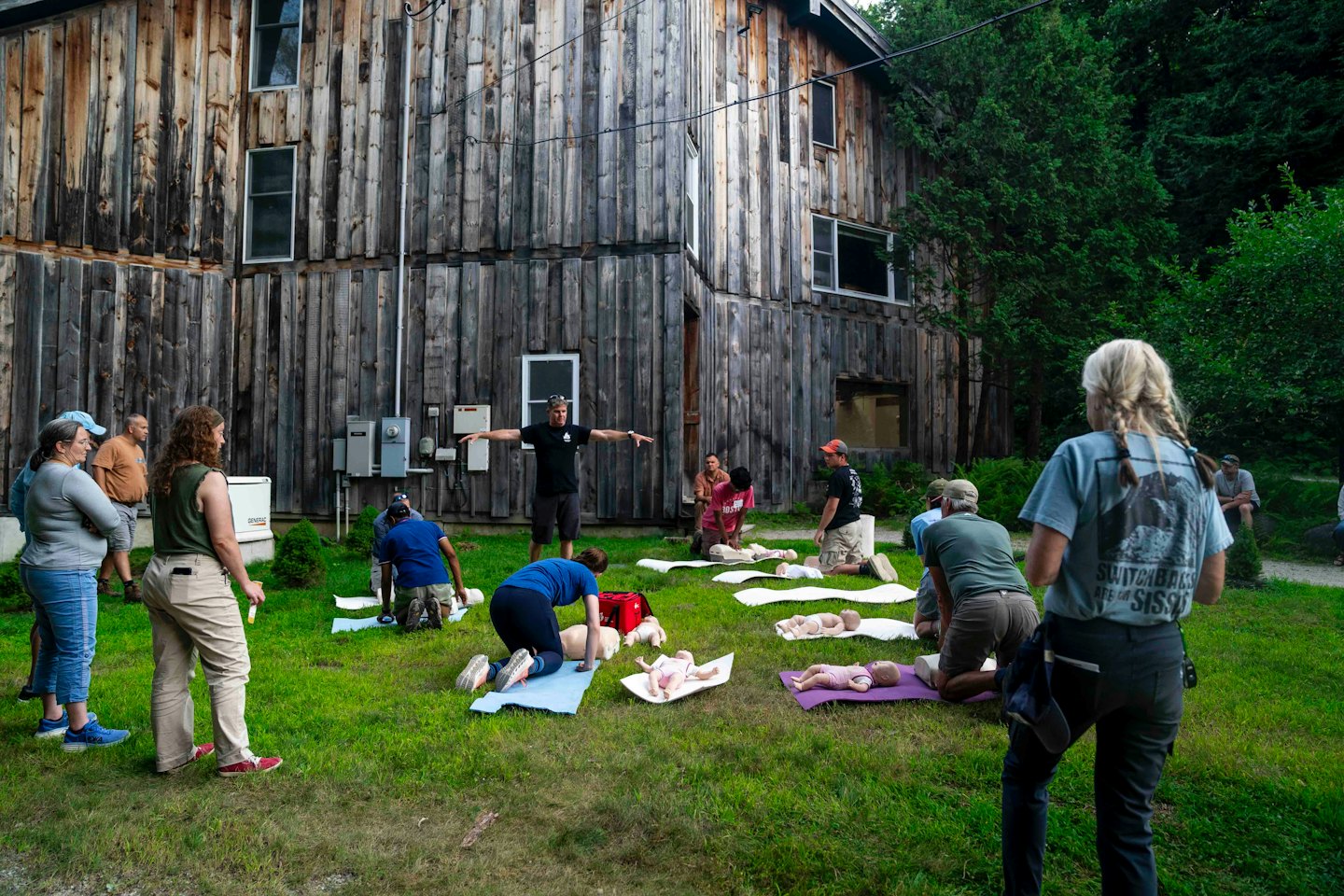 Students practice CPR on mannequins during an outdoor training session.